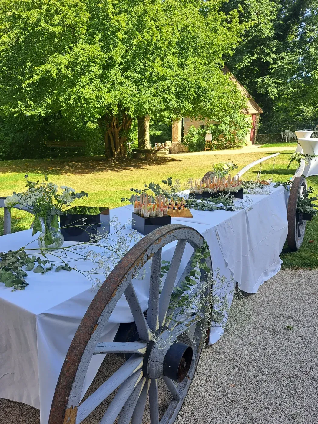Buffet de réception dressé en plein air, décoré d’une roue de charrette
